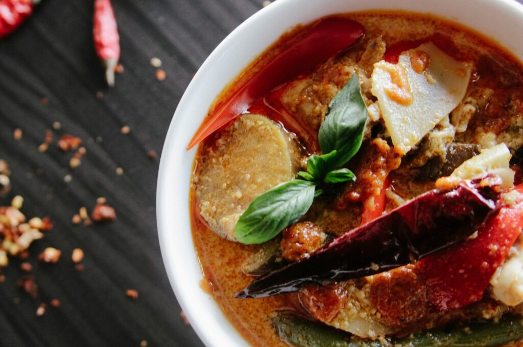 A serving of Thai curry featuring a mix of fresh vegetables and spices, presented in a traditional bowl.