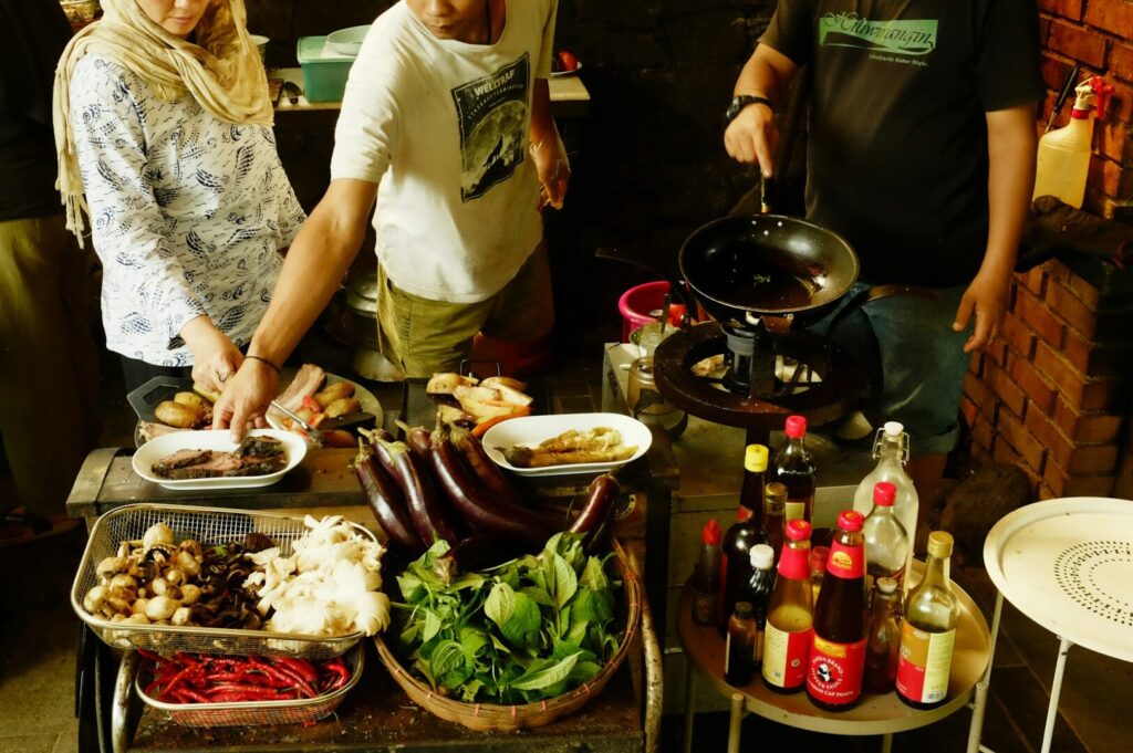 Participants in a Thai cooking class collaborate around a table, preparing various ingredients for their dishes.