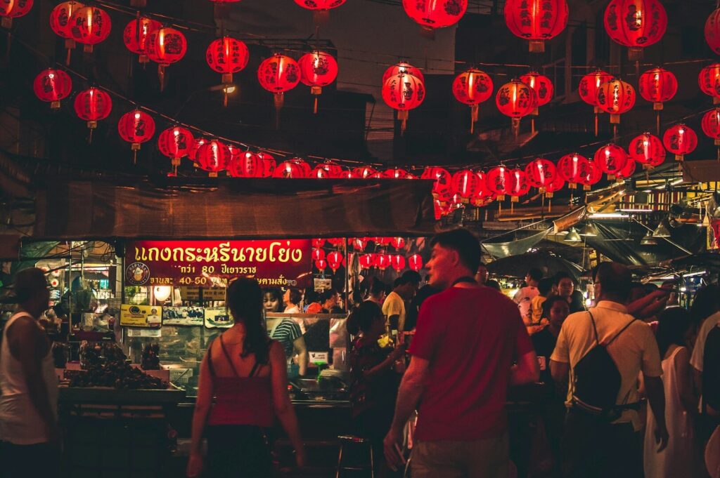 Visitors explore an Asian market filled with red lanterns, capturing the essence of a Bangkok food tour.