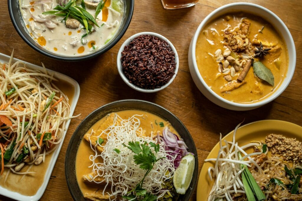 A wooden table set with an array of traditional Thai dishes, highlighting the art of home cooking.