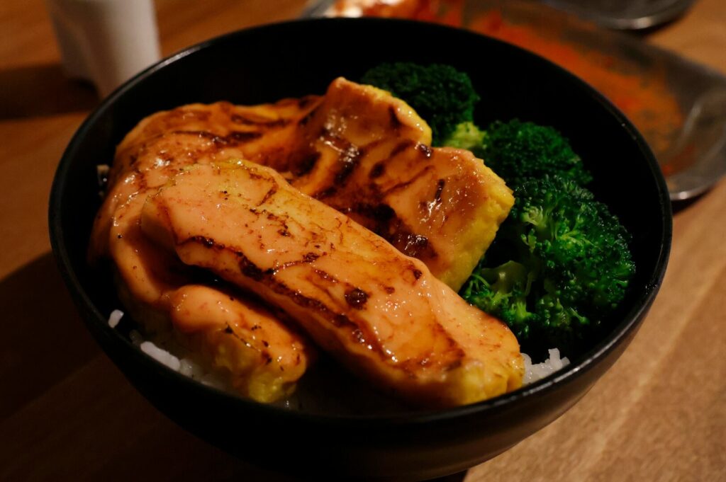 A vibrant bowl of vegan Japanese cuisine with broccoli and plant-based meat, highlighting a healthy dining option.