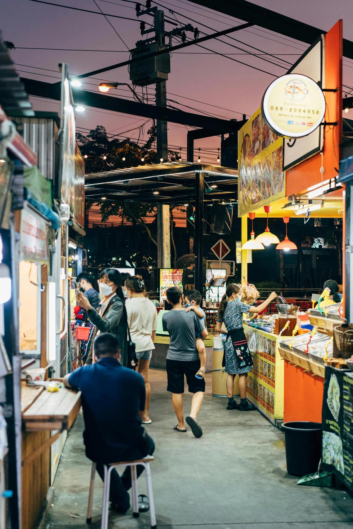 Tourists exploring a vibrant night street food market filled with local vendors and dishes.