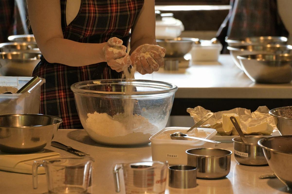 Participant mixing flour in a glass bowl during a hands-on cooking class experience.