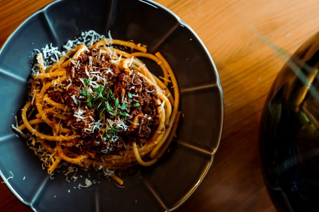 Spaghetti served with savory meat and a sprinkle of parmesan, representing traditional Italian cuisine from a regional guide.