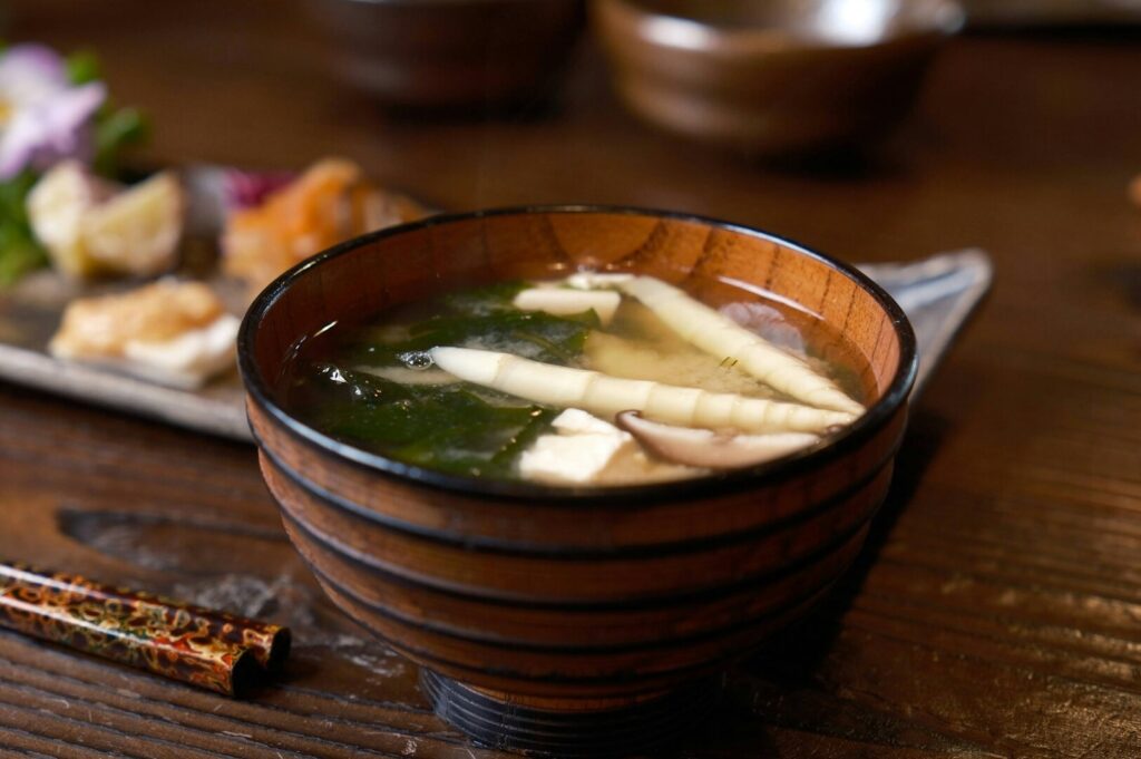 A bowl of steaming miso soup accompanied by chopsticks, highlighting a traditional Japanese dining experience.