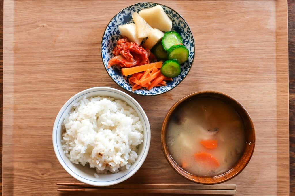 A colorful bowl of rice and mixed vegetables with a side of soup, representing a healthy plant-based meal.