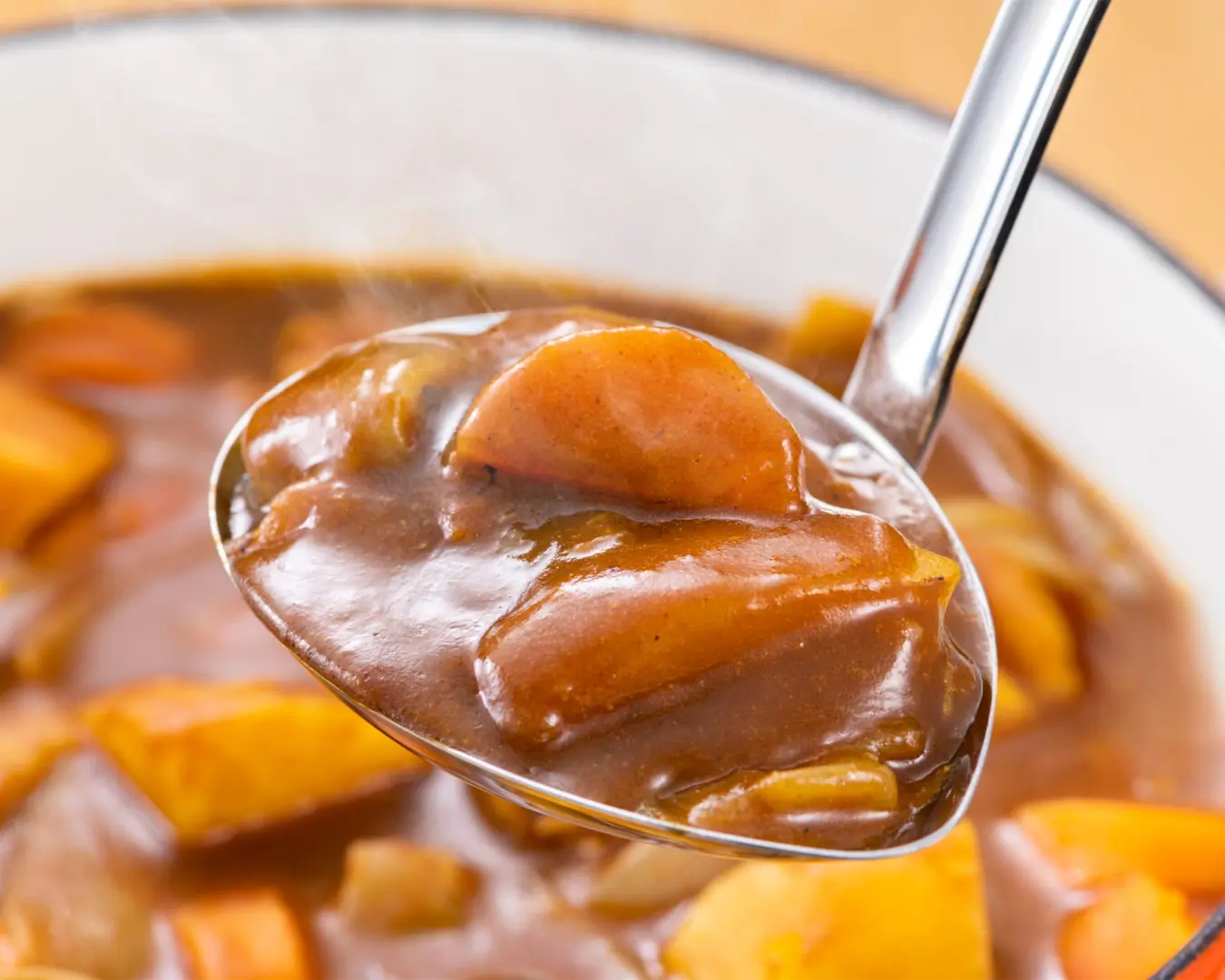 A rich bowl of Japanese curry with a thick, glossy sauce, slowly simmered with vegetables and spices, creating a warm and comforting dish known for its mild sweetness and deep umami flavour.