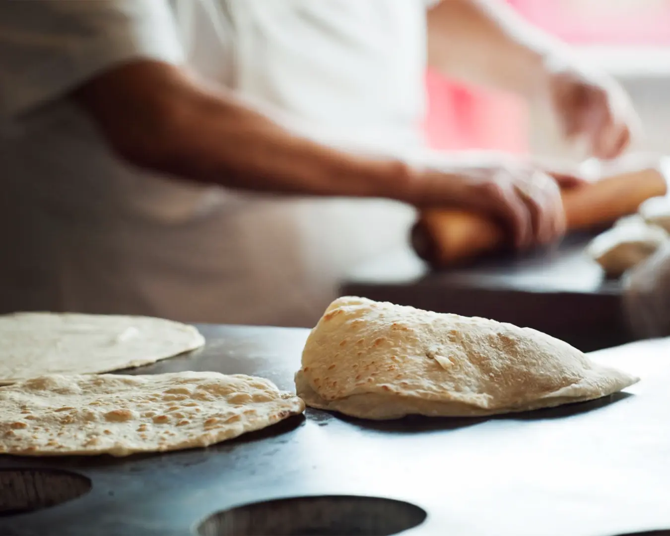 Fresh naan bread cooking on a hot grill, with the surface blistering and browning as it bakes, capturing the authentic process of making traditional flatbread.
