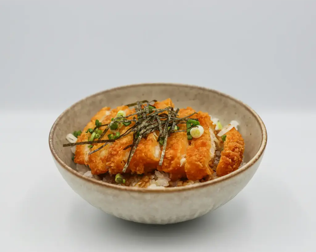 A hearty bowl of Japanese katsu curry featuring crispy breaded cutlet served over rice and topped with thick, savoury curry sauce, combining crunchy texture with rich, comforting flavour.