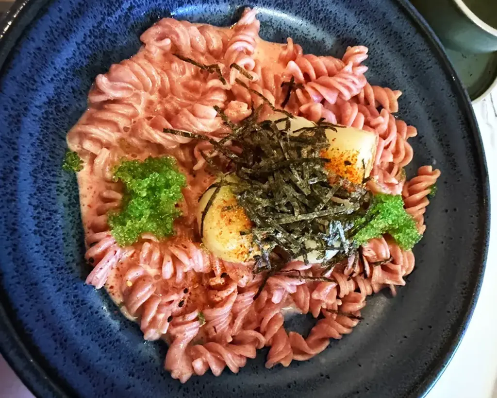 A plate of pasta tossed with cherry tomatoes, garlic, and olive oil, lightly coated to create a simple yet aromatic dish with bright red tomatoes and a glossy finish.