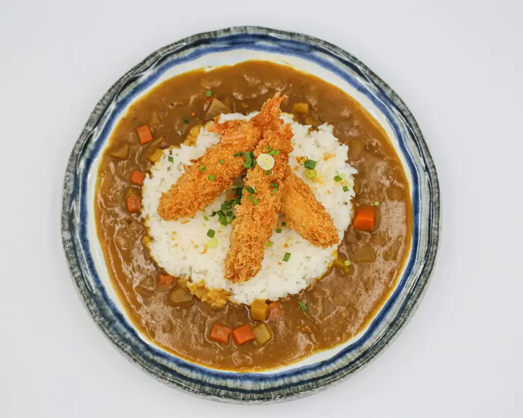 A hearty bowl of Japanese katsu curry featuring crispy breaded cutlet served over rice and topped with thick, savoury curry sauce, combining crunchy texture with rich, comforting flavour.