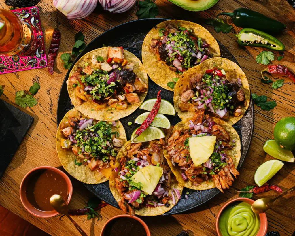 Soft corn tortillas folded into tacos and filled with seasoned chicken and toppings, presented as a simple and flavourful handheld meal.