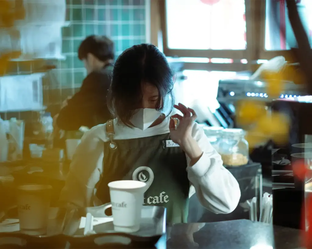 A barista carefully preparing coffee behind the counter, focusing on the craft as they handle the espresso machine and create a freshly brewed cup.