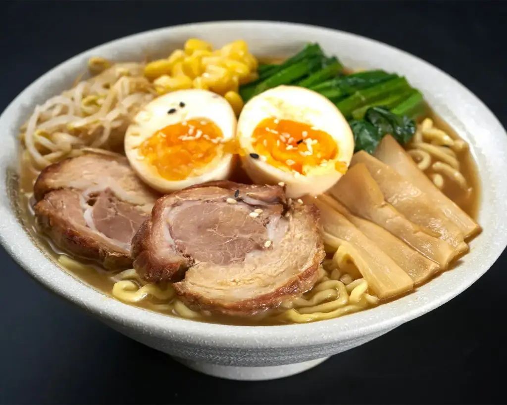 A delicious bowl of ramen with tender meat, creamy eggs, and vibrant vegetables.