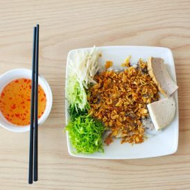 Vietnamese steamed rice sheets topped with fried shallots, herbs, and sliced pork sausage served with dipping sauce